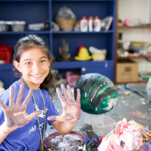 Female camper with hands covered in paint