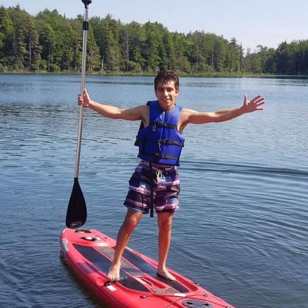 Male camper with arms aloft on a Paddleboard