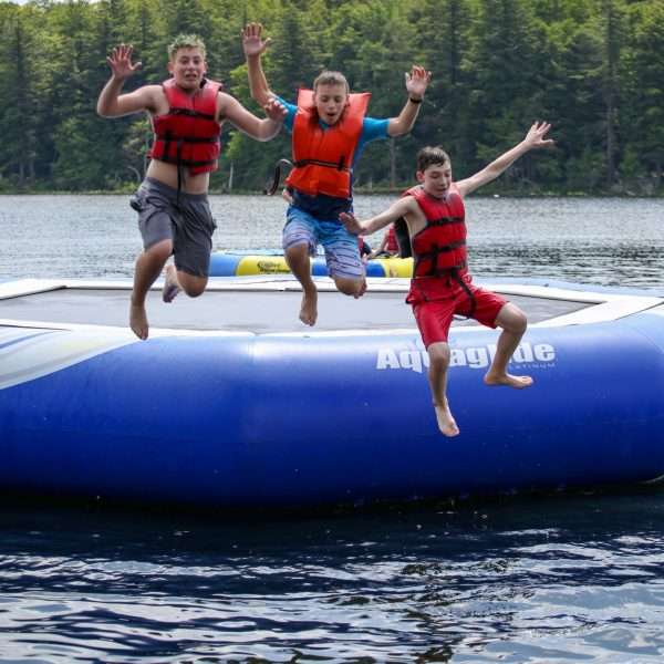 Campers jumping into the lake from a large inflatable