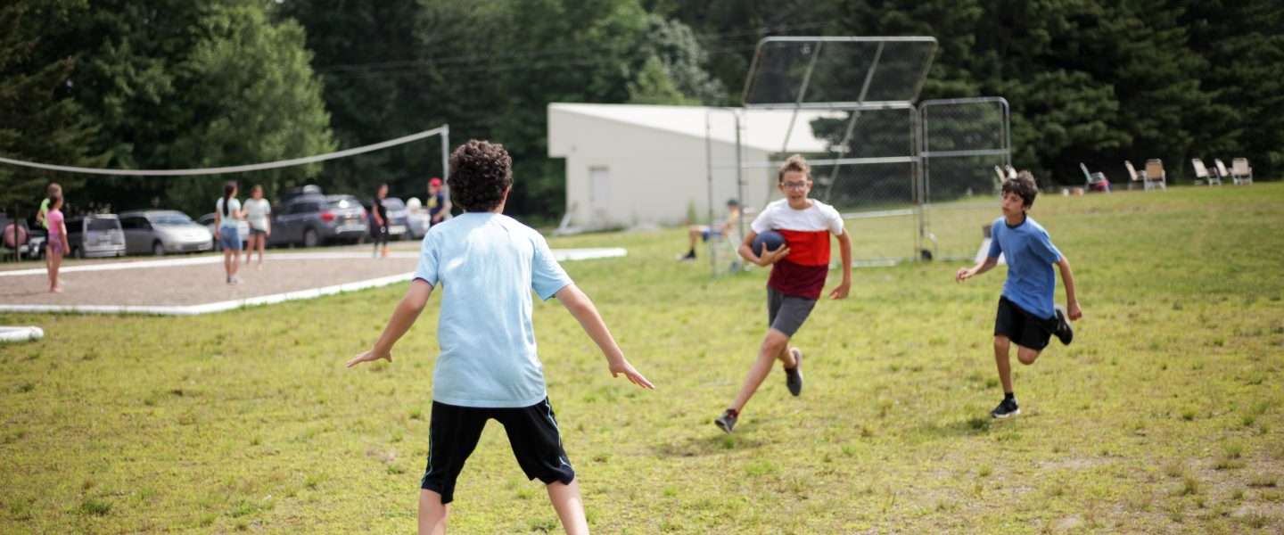 Three campers playing flag football