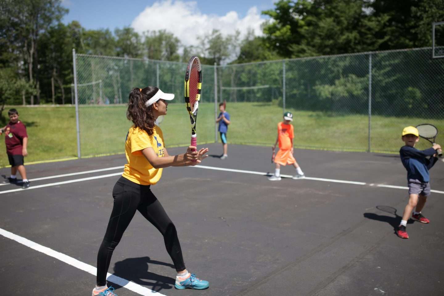 One of the camp counselors playing tennis with campers