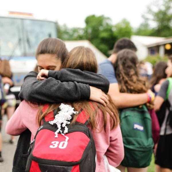 Campers hugging each other with a bus in the background