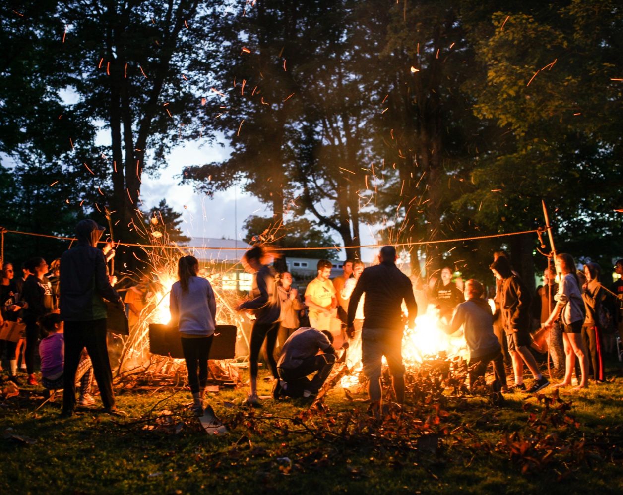 Group of campers around a camp fire at dusk