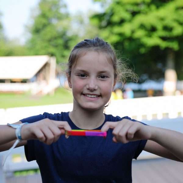 Female camper holding one of the Camp Zeke bracelets