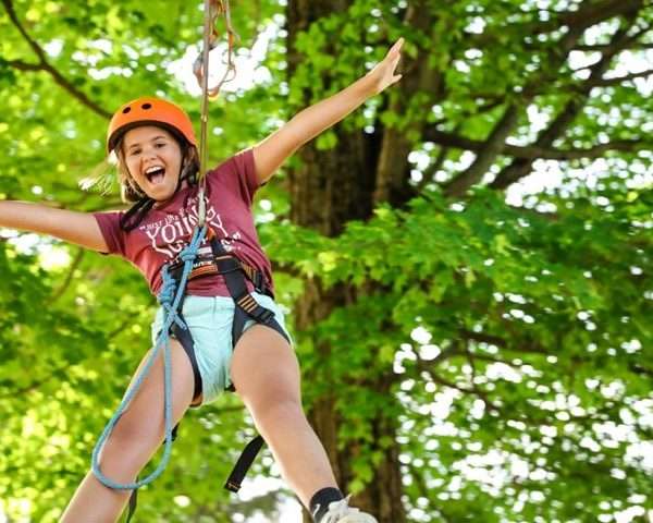 Photo of a female camper on a high-wire within trees