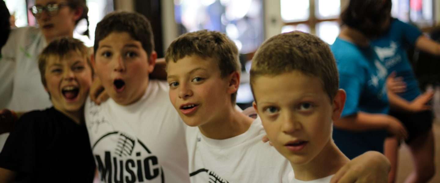 Group of young male campers with arms around each other singing