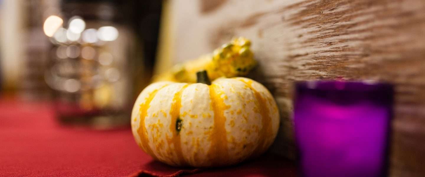 Close up photo of a candle and gourds used to decorate a table