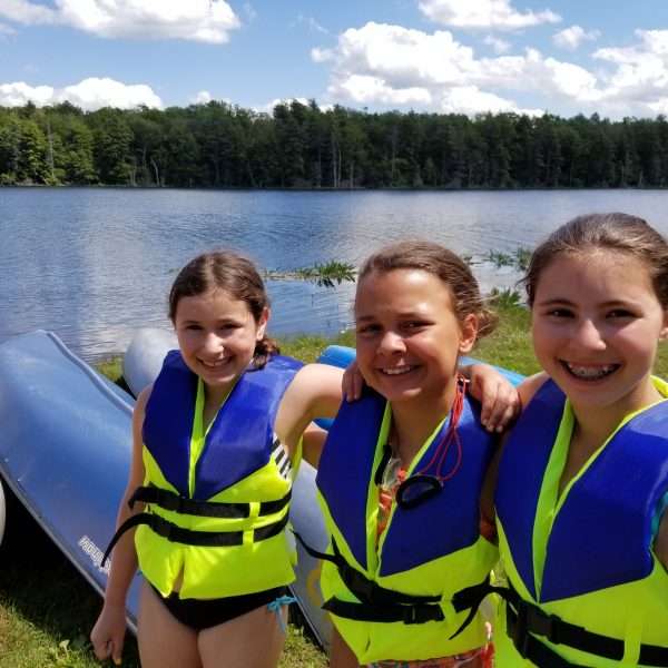 Three female campers in lifejackets waiting to go waterskiing