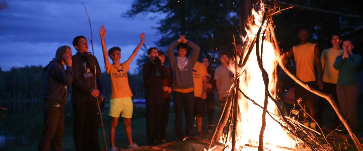 Group of campers around a roaring fire in the dark